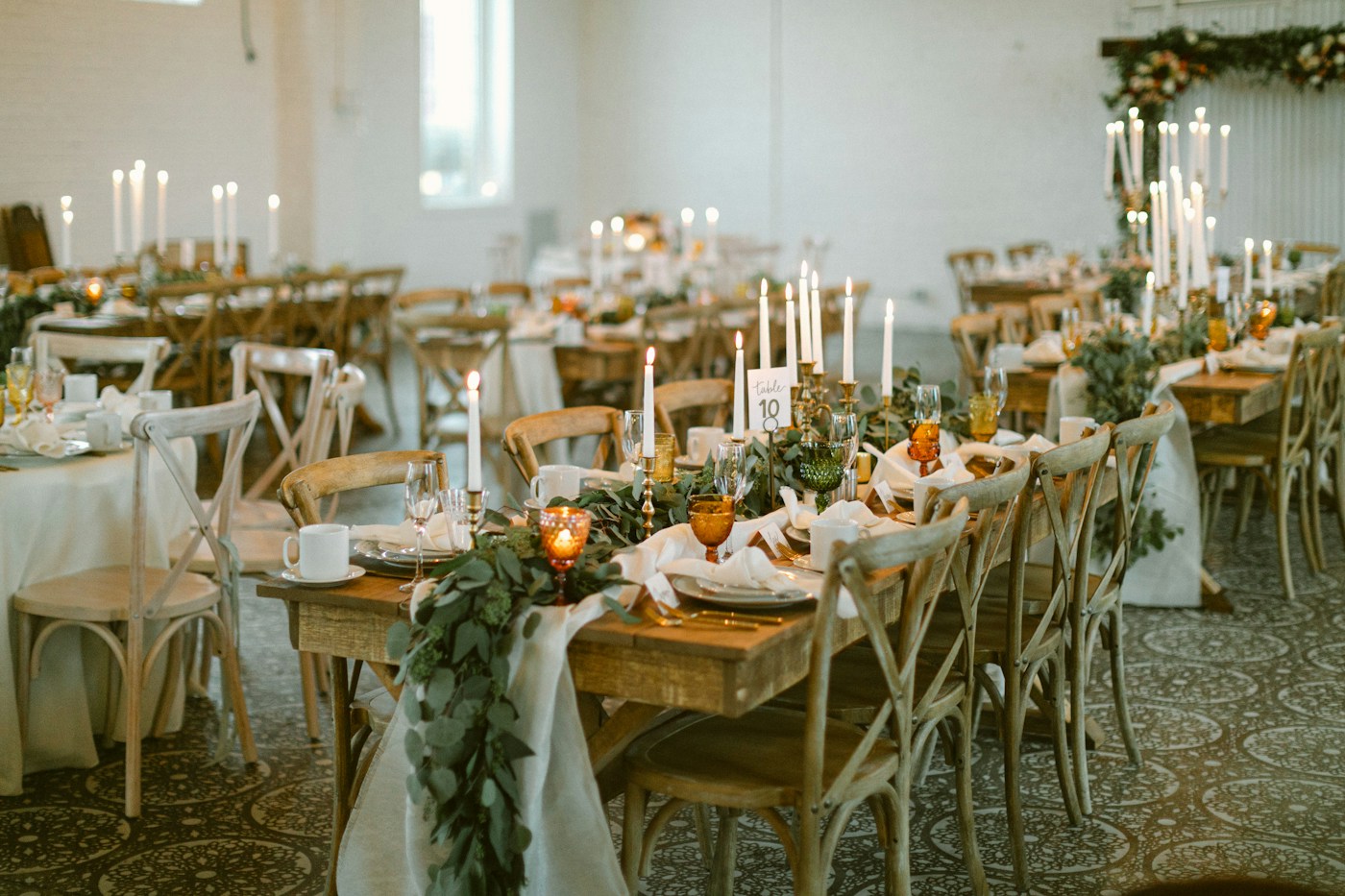 Wedding reception tables with candles and greenery